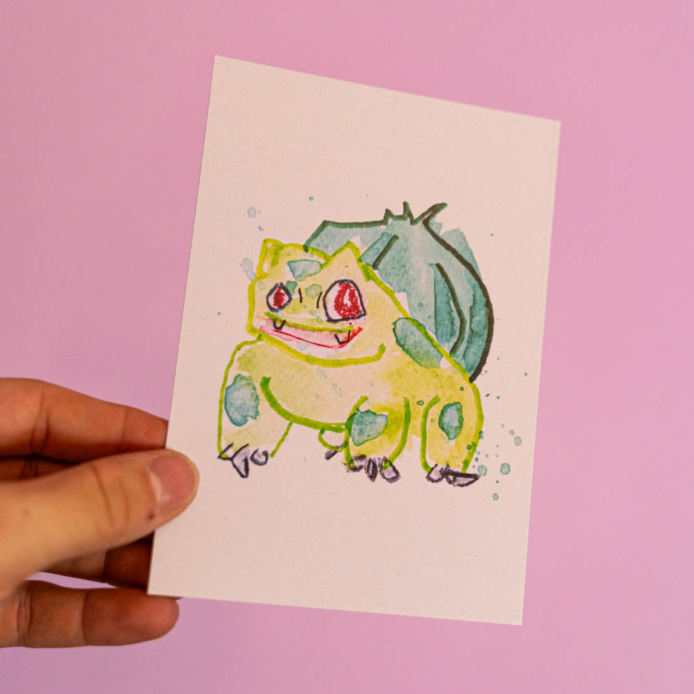 Carte postale Bulbizarre (Edition Moche) -Carte postale imprimée d’une illustration réalisée à l'aquarelle et aux crayons de couleurs.Le dessin vient d'un challenge en live sur Twitch dans lequel j'ai dessiné les 151 Pokémon de la première génération de 1995 en 24h en live sur Twitch, MAIS : en moche ! Voir la vidéo : https://youtu.be/0MyLD5bqc1Q Papier 300g recyclé. Possibilité de la faire signer et dédicacer à la main en choisissant l'option de livraison "Dédicacée".-Brunograffer Carte postale Bulbizarre (Edition Moche) -Carte postale imprimée d’une illustration réalisée à l'aquarelle et aux crayons de couleurs.Le dessin vient d'un challenge en live sur Twitch dans lequel j'ai dessiné les 151 Pokémon de la première génération de 1995 en 24h en live sur Twitch, MAIS : en moche ! Voir la vidéo : https://youtu.be/0MyLD5bqc1Q Papier 300g recyclé. Possibilité de la faire signer et dédicacer à la main en choisissant l'option de livraison