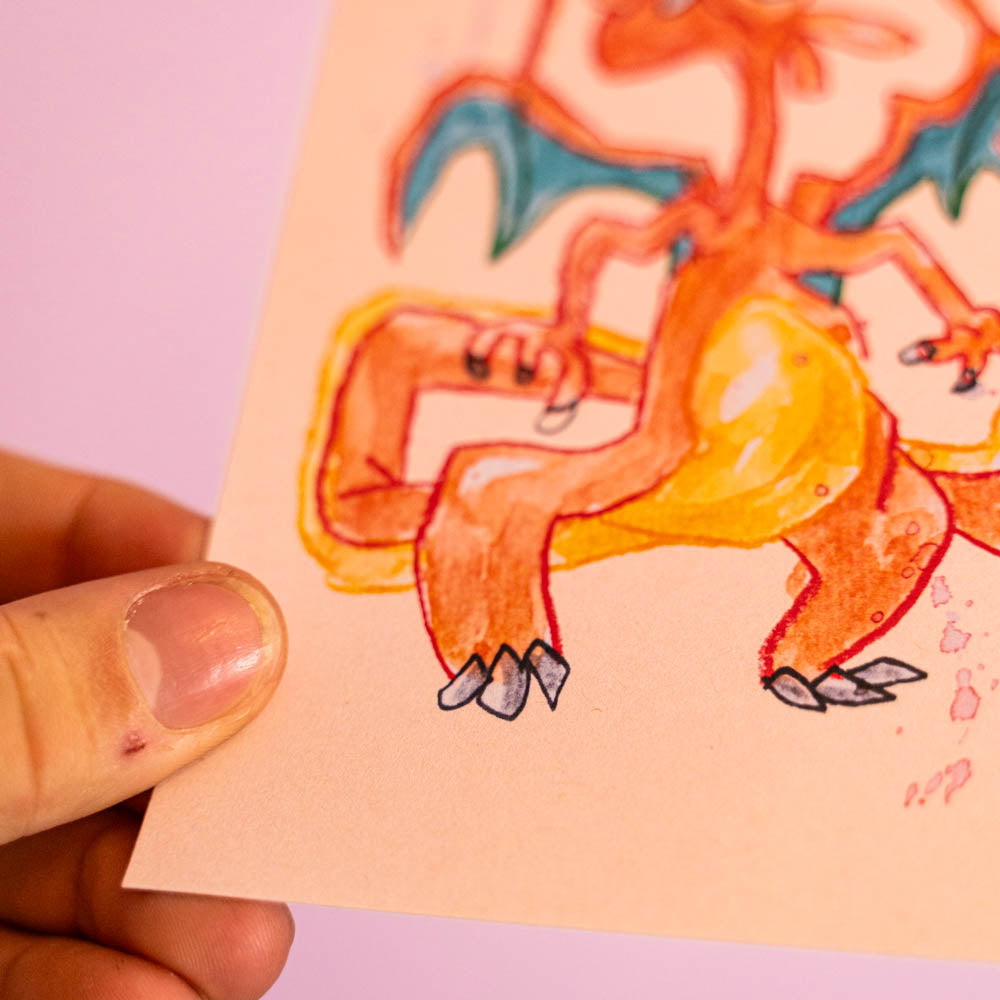 Carte postale Dracaufeu (Edition Moche) -Carte postale imprimée d’une illustration réalisée à l'aquarelle et aux crayons de couleurs.Le dessin vient d'un challenge en live sur Twitch dans lequel j'ai dessiné les 151 Pokémon de la première génération de 1995 en 24h en live sur Twitch, MAIS : en moche ! Voir la vidéo : https://youtu.be/0MyLD5bqc1Q Papier 300g recyclé. Possibilité de la faire signer et dédicacer à la main en choisissant l'option de livraison "Dédicacée".-Brunograffer