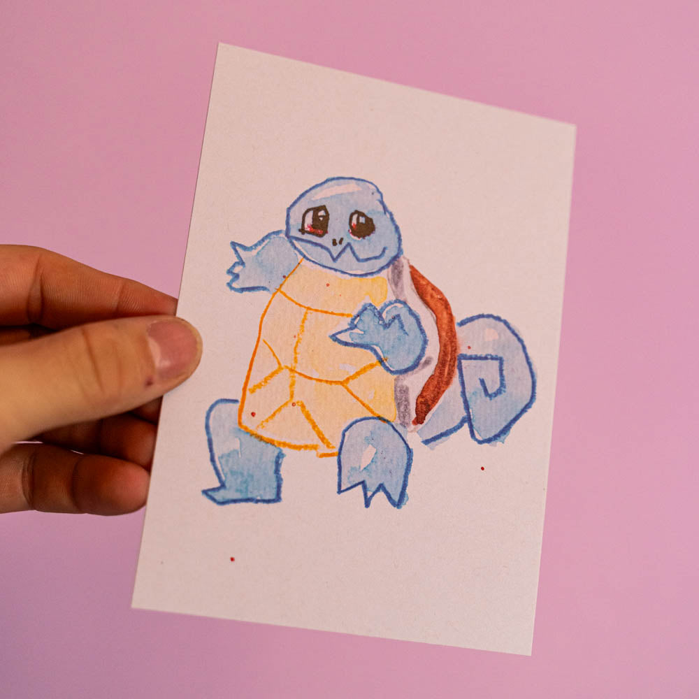 Carte postale Carapuce (Edition Moche) -Carte postale imprimée d’une illustration réalisée à l'aquarelle et aux crayons de couleurs.Le dessin vient d'un challenge en live sur Twitch dans lequel j'ai dessiné les 151 Pokémon de la première génération de 1995 en 24h en live sur Twitch, MAIS : en moche ! Voir la vidéo : https://youtu.be/0MyLD5bqc1Q Papier 300g recyclé. Possibilité de la faire signer et dédicacer à la main en choisissant l'option de livraison "Dédicacée".-Brunograffer