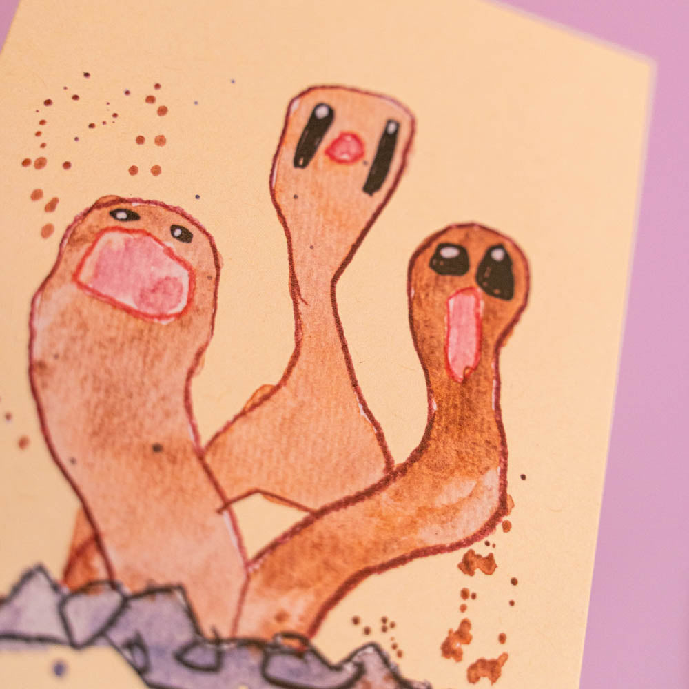 Carte postale Triopiqueur (Edition Moche) -Carte postale imprimée d’une illustration réalisée à l'aquarelle et aux crayons de couleurs.Le dessin vient d'un challenge en live sur Twitch dans lequel j'ai dessiné les 151 Pokémon de la première génération de 1995 en 24h en live sur Twitch, MAIS : en moche ! Voir la vidéo : https://youtu.be/0MyLD5bqc1Q Papier 300g recyclé. Possibilité de la faire signer et dédicacer à la main en choisissant l'option de livraison 